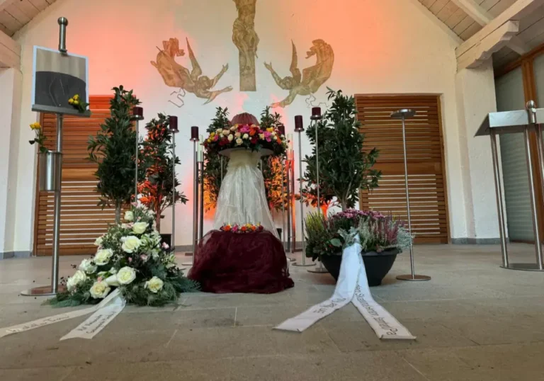 Aufbau einer Trauerfeier in der Aussegnungshalle mit Blumenschmuck, Kerzen und Kränzen