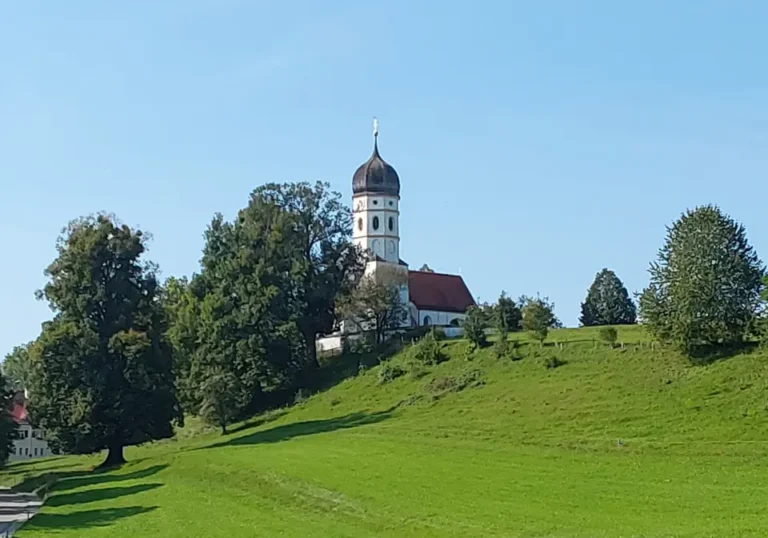 Kirche Holzhausen auf dem grünen Kirchhügel zwischen alten Bäumen